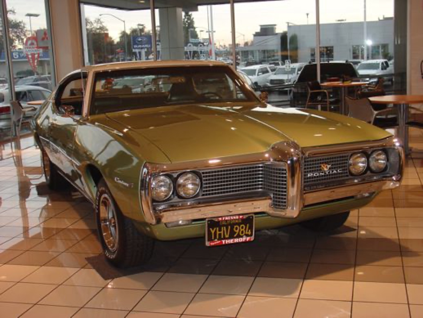 Gleaming gold Pontiac hardtop under showroom lights