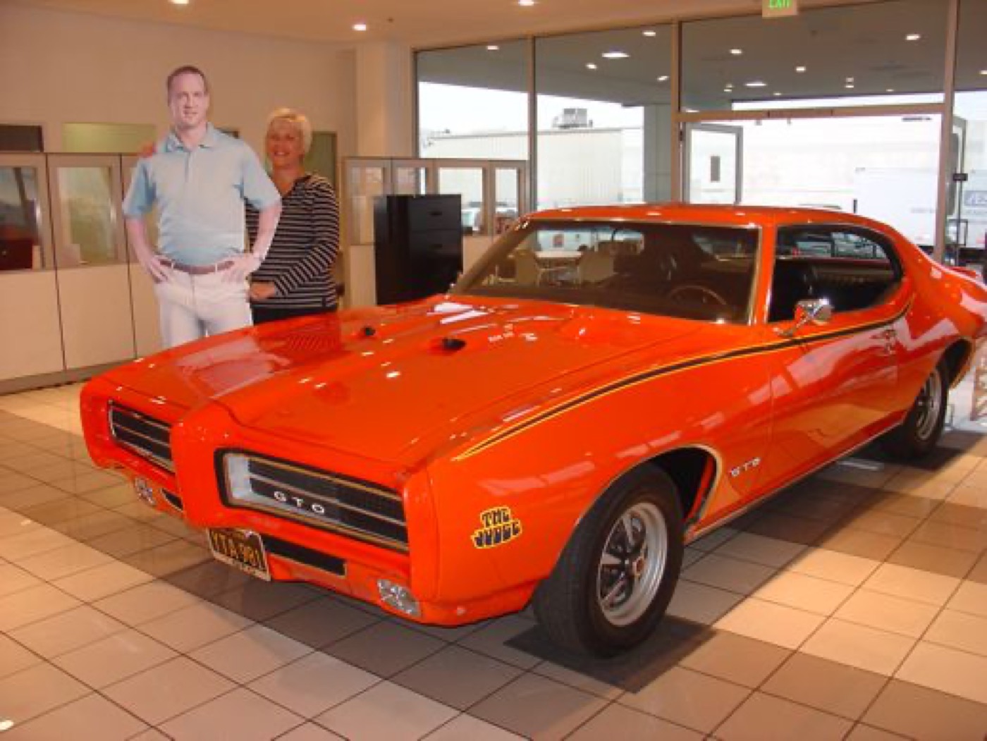 Proud couple beside their striking orange GTO Judge
