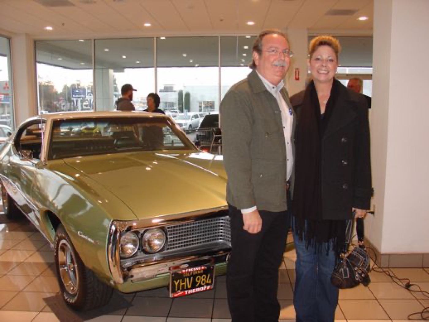 Happy couple posing with classic green Pontiac
