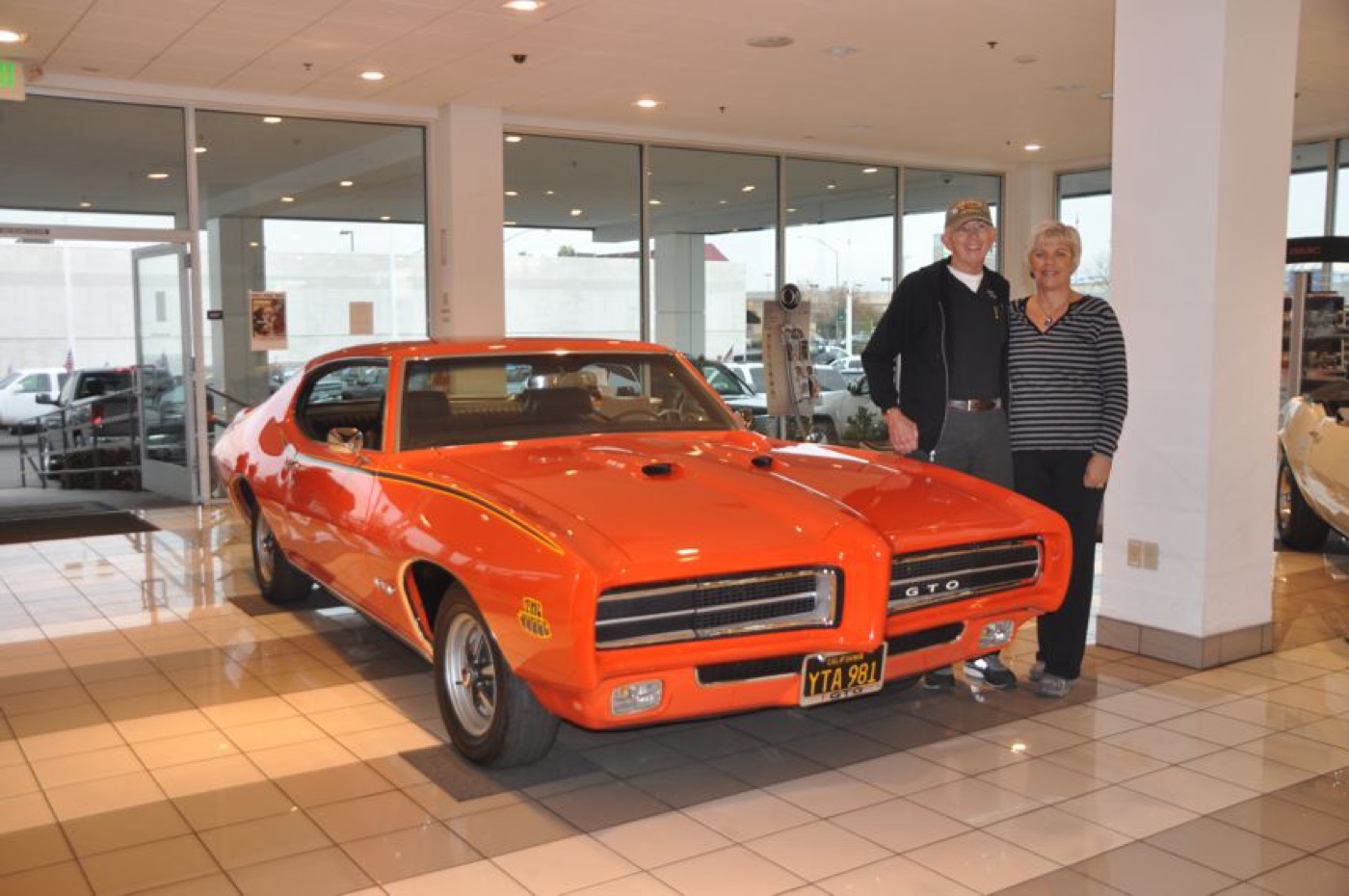 Proud couple beside gleaming orange GTO