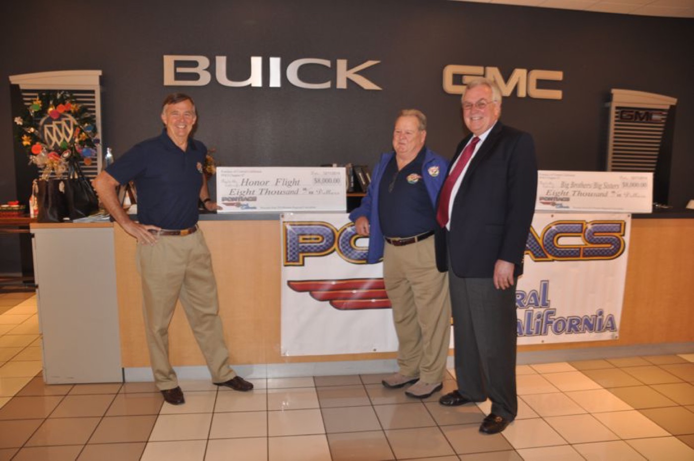 Members presenting donation checks at club banner