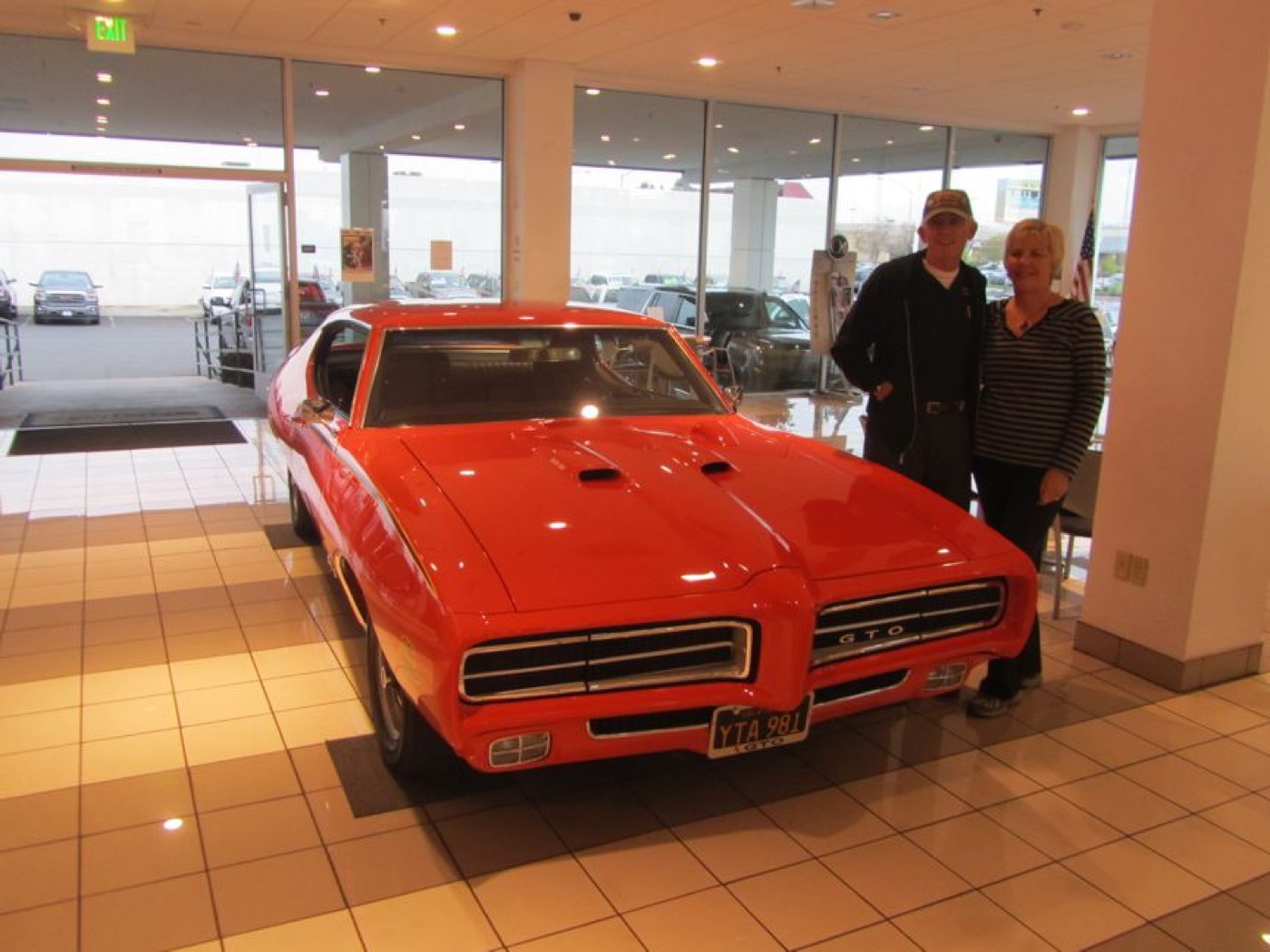 Proud couple beside bright red GTO Judge