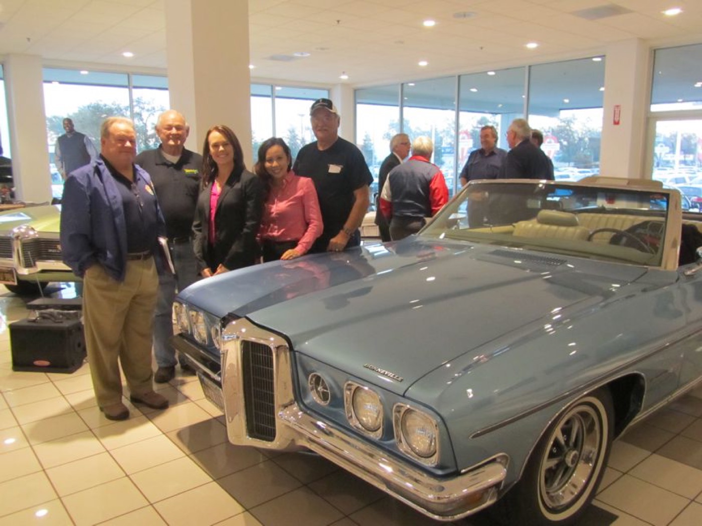 Club friends gathered around blue convertible