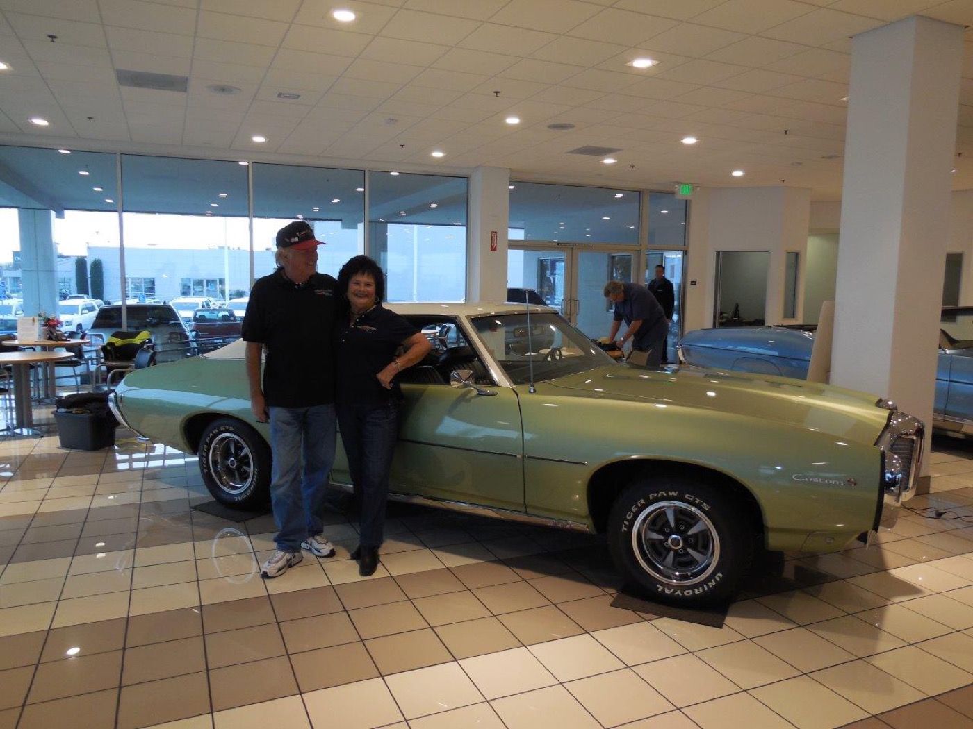 Proud couple beside gleaming green Pontiac classic