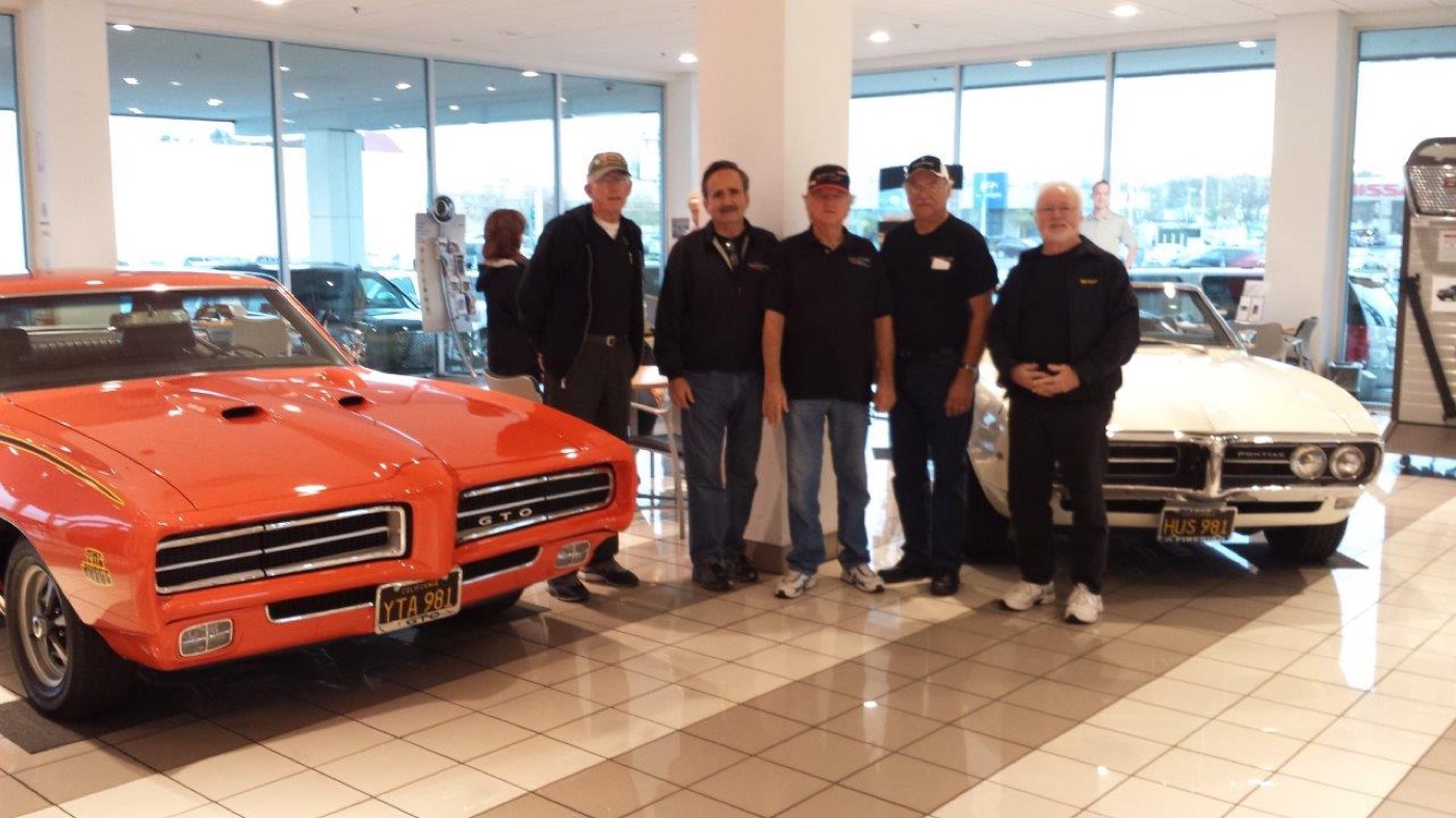 Club members gathered between two classic Pontiacs