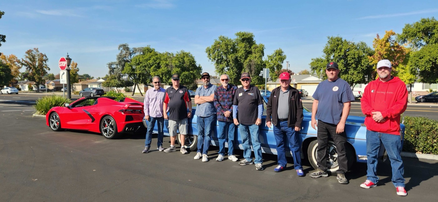 Club lineup gathered behind a red Corvette